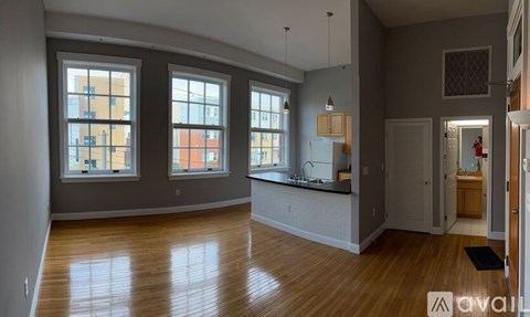 A spacious room with wooden floors and large windows.