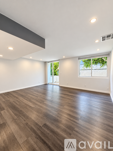 A spacious room with wooden flooring and a large window.