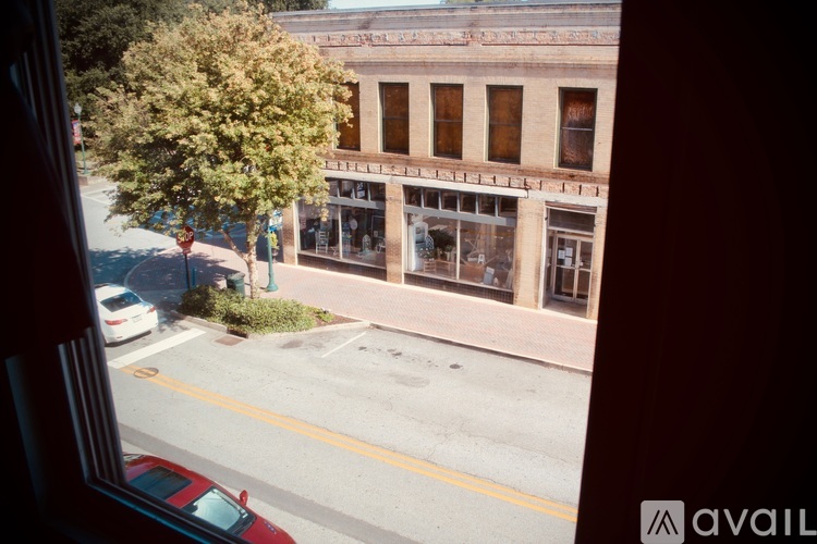 A view of a street from a window with a car parked on the side.