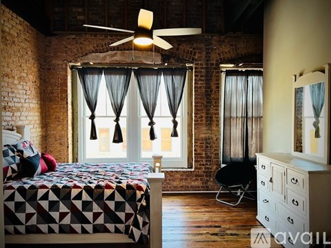 A bedroom with a brick wall and a bed with a black and white comforter.