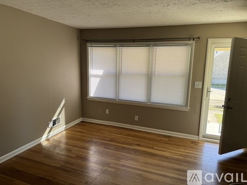 A room with wooden flooring and a window with blinds.