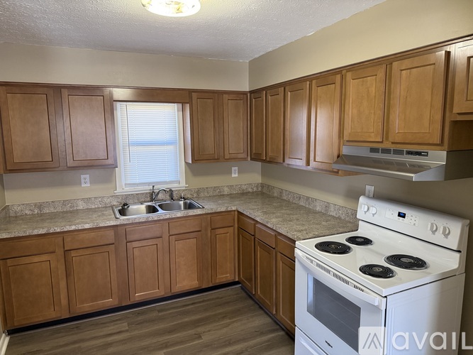 A kitchen with wooden cabinets and a white stove top oven.