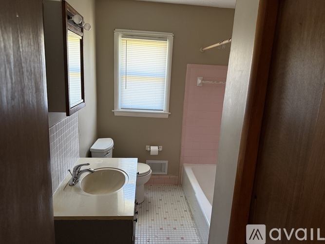 A bathroom with a sink, toilet, and window.