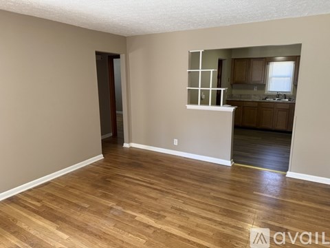 A room with wooden flooring and a white wall with a window.