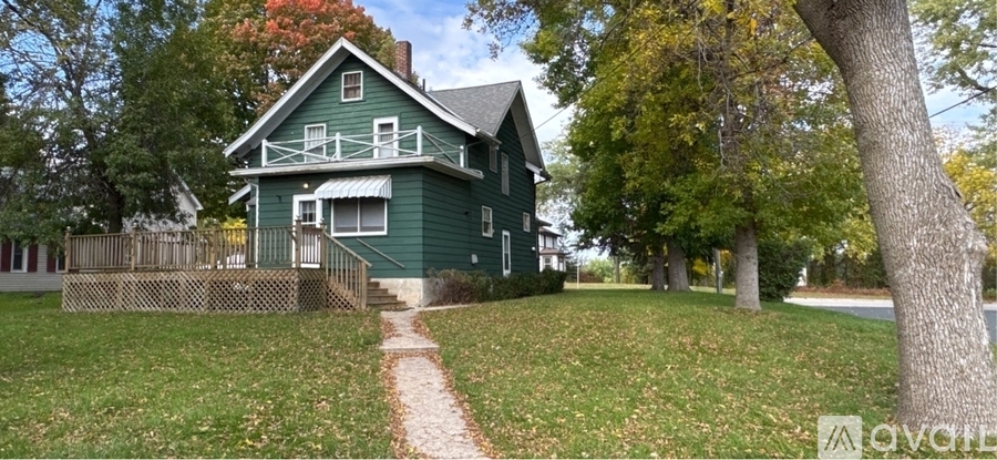 A green house with a wooden fence and a tree in front.