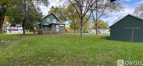 A green house with a fence and a shed in a grassy area.