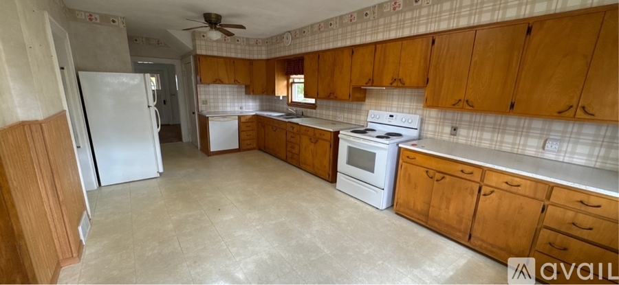 A kitchen with wooden cabinets and a white stove top oven.