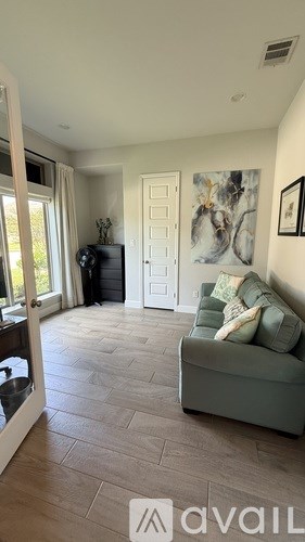 A living room with a green couch and a painting on the wall.
