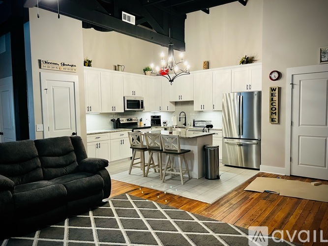 A kitchen with a black couch and a wooden floor.
