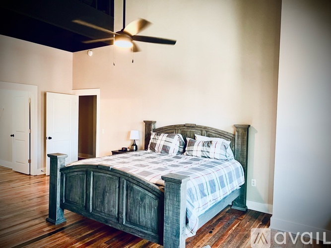 A bedroom with a bed, a ceiling fan, and a wooden floor.
