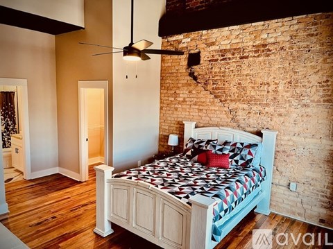 A bedroom with a brick wall and a bed with a black and white comforter.