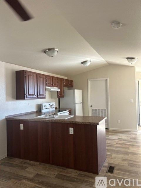 A kitchen with brown cabinets and a white fridge.
