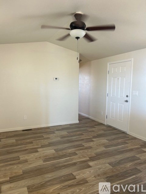 A room with a ceiling fan and wooden flooring.