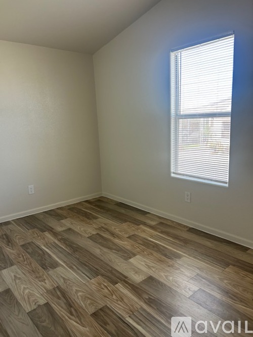 A room with wooden flooring and a window with blinds.