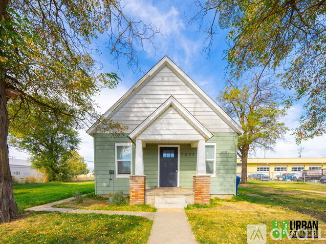A small house with a green front yard is for sale.