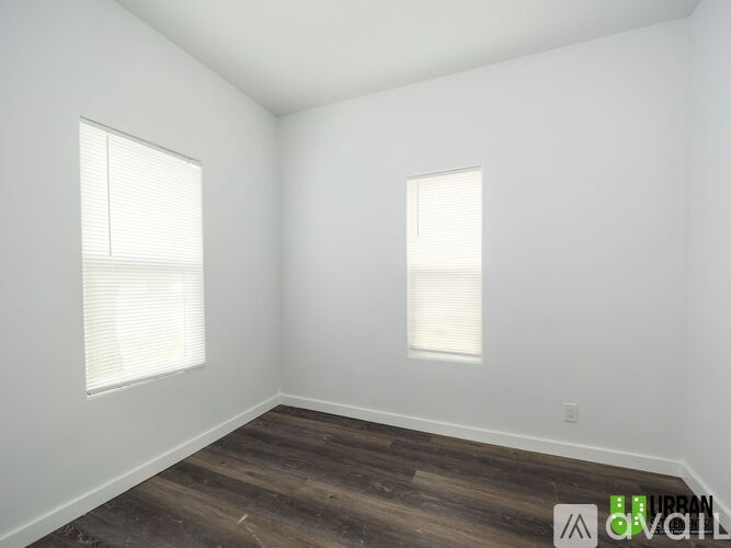 A room with wooden floors and two windows.