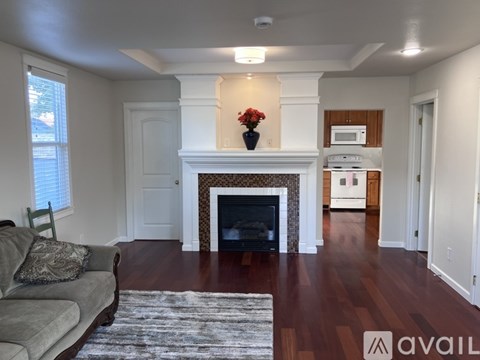 A living room with a fireplace and a grey couch.