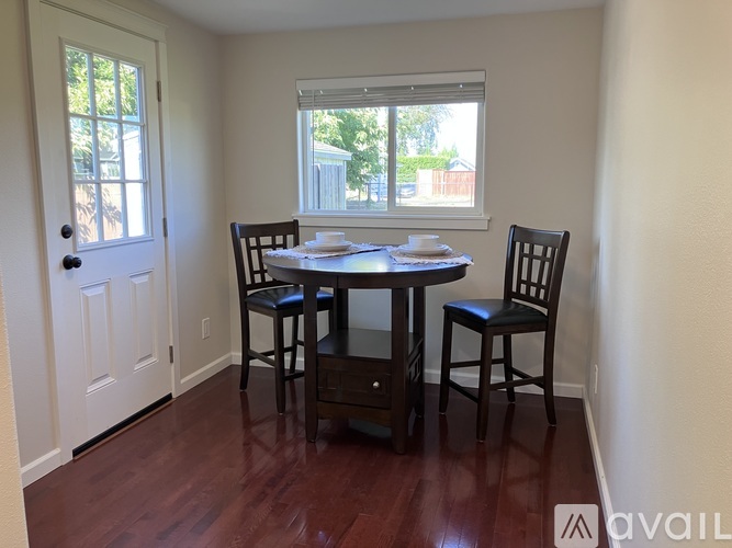 A dining room with a table set for two and a window.