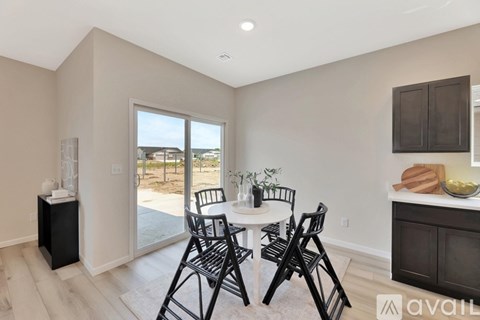 A dining room with a table set for four and a view of the backyard.