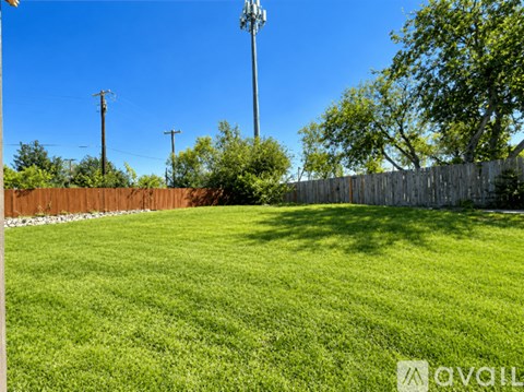 A grassy field with a wooden fence and trees in the background.