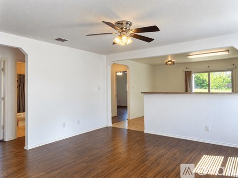 A spacious room with a ceiling fan and hardwood floors.