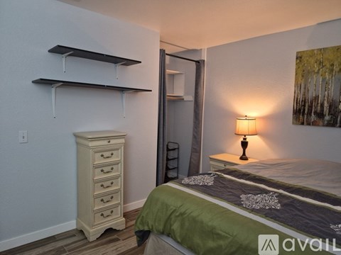 A bedroom with a bed, nightstand, and a cabinet with shelves.