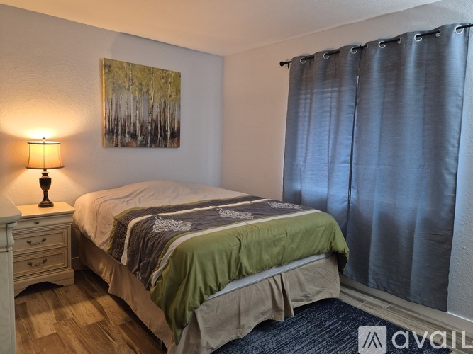 A bedroom with a bed, nightstand, and a painting on the wall.