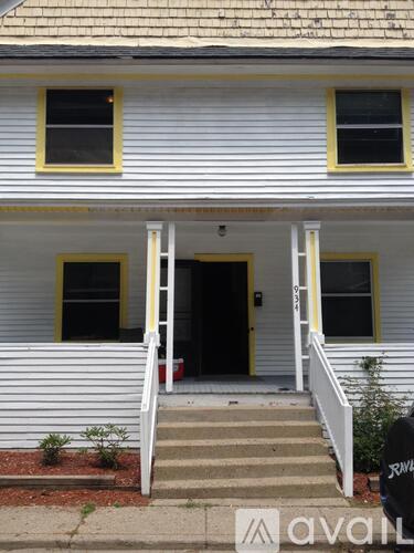 A white house with a yellow trim and a red mailbox.