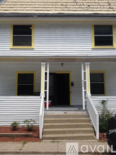 A white house with a yellow trim and a red mailbox.