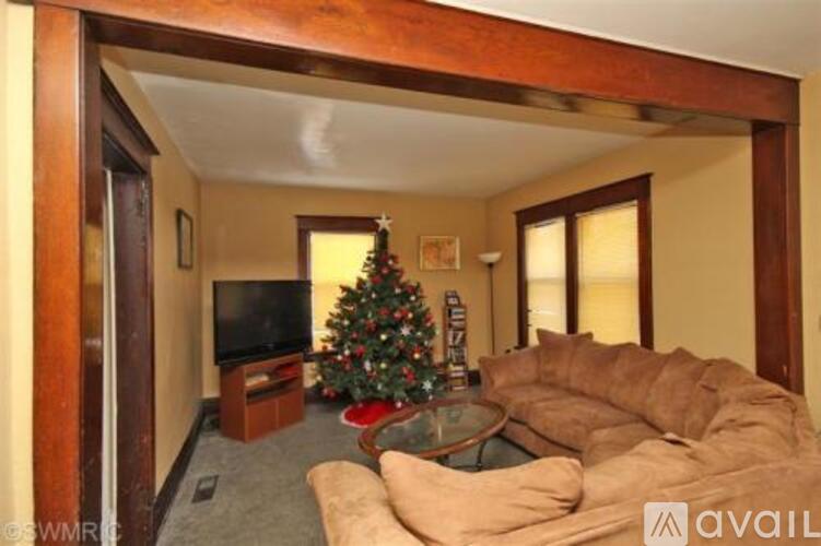 A living room with a Christmas tree and a television.