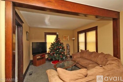 A living room with a Christmas tree and a television.