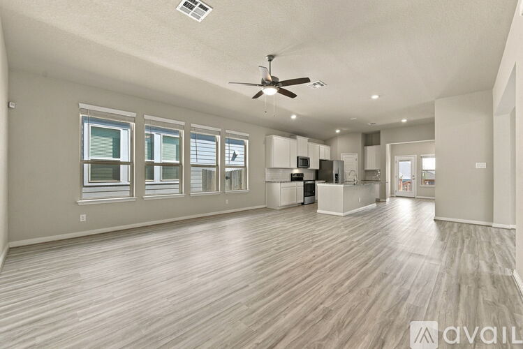 A spacious room with wooden flooring and a ceiling fan.