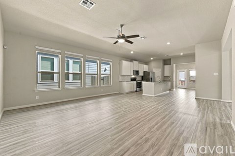 A spacious room with wooden flooring and a ceiling fan.