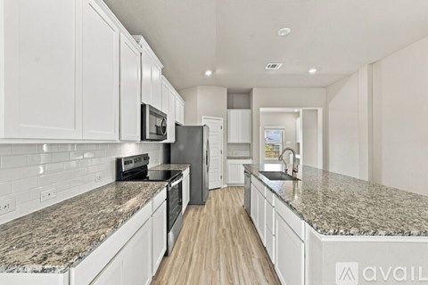 A kitchen with granite countertops and white cabinets.