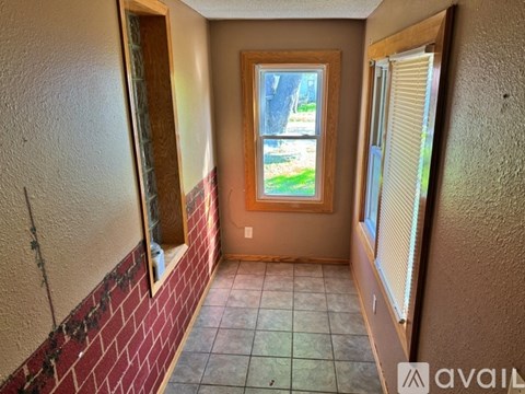 A hallway with a brick wall and a window with a view of a tree and a lawn.