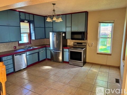 A kitchen with blue cabinets and a stainless steel refrigerator.