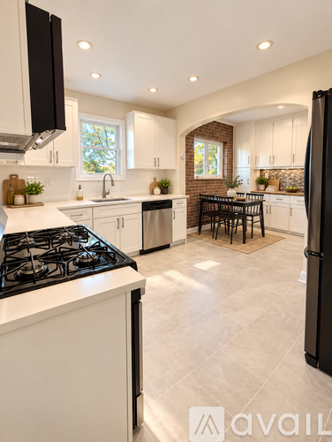 A modern kitchen with a black stove top and white cabinets.