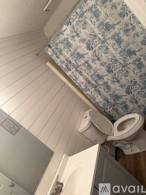 A toilet in a bathroom with a floral shower curtain.