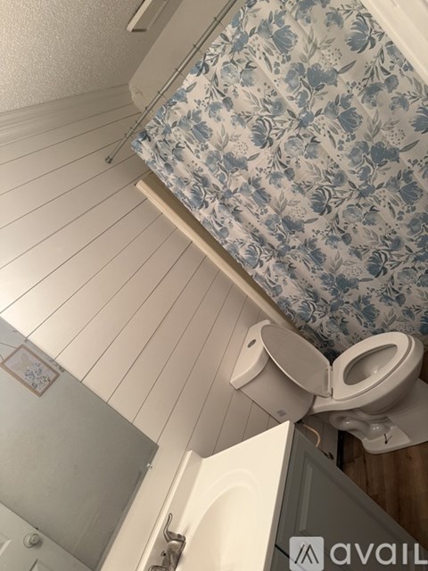 A toilet in a bathroom with a floral shower curtain.
