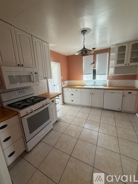 A kitchen with white cabinets and a tile floor.