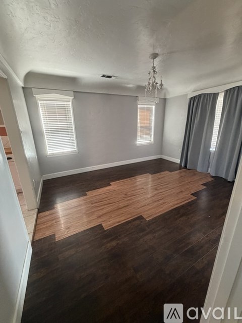 A room with wooden flooring and a chandelier.