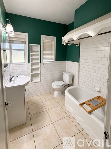 A bathroom with green walls and white fixtures.