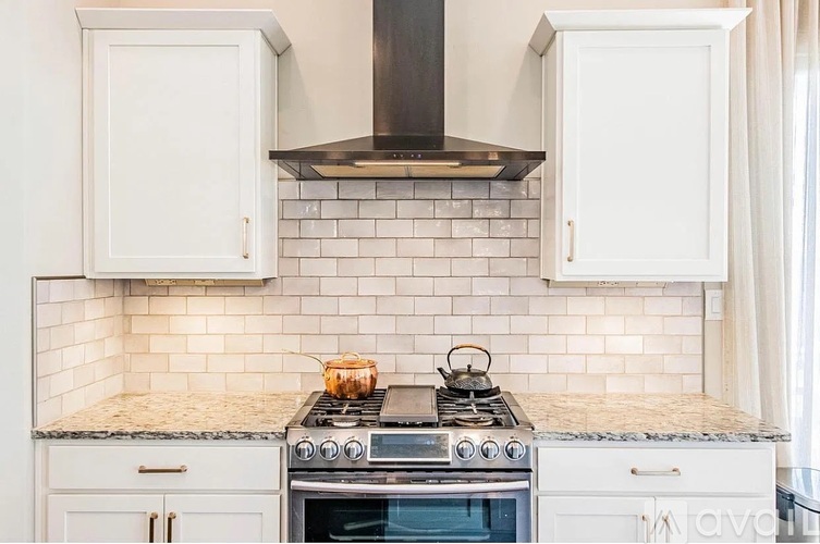 A kitchen with a stove top oven and white cabinets.