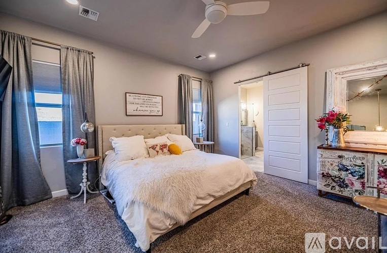 A bedroom with a large bed, a ceiling fan, and a mirror.