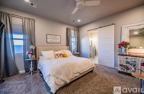 A bedroom with a large bed, a ceiling fan, and a mirror.