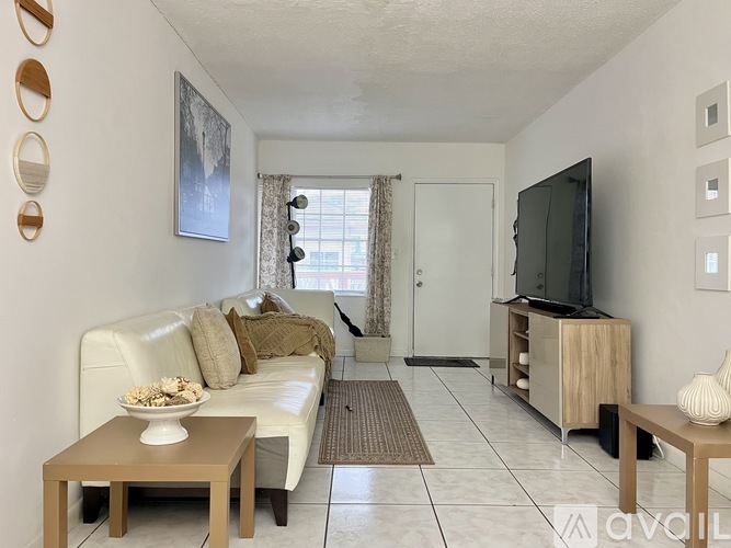 A living room with a white couch, a coffee table, and a television.