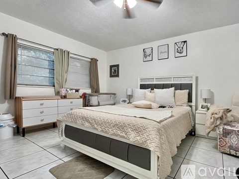 A bedroom with a large bed, a dresser with a window, and a ceiling fan.