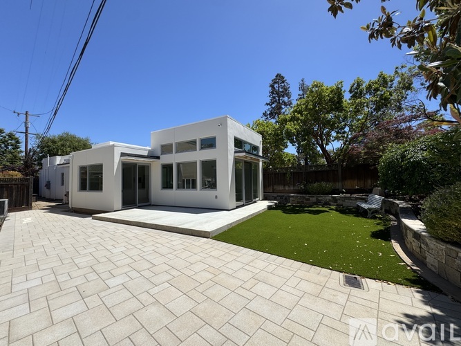 A modern white house with a paved walkway in front.