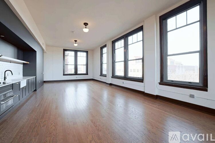 A spacious room with wooden floors and large windows.