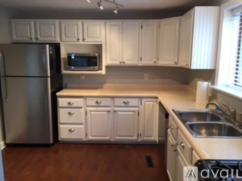 A kitchen with white cabinets and a stainless steel refrigerator.
